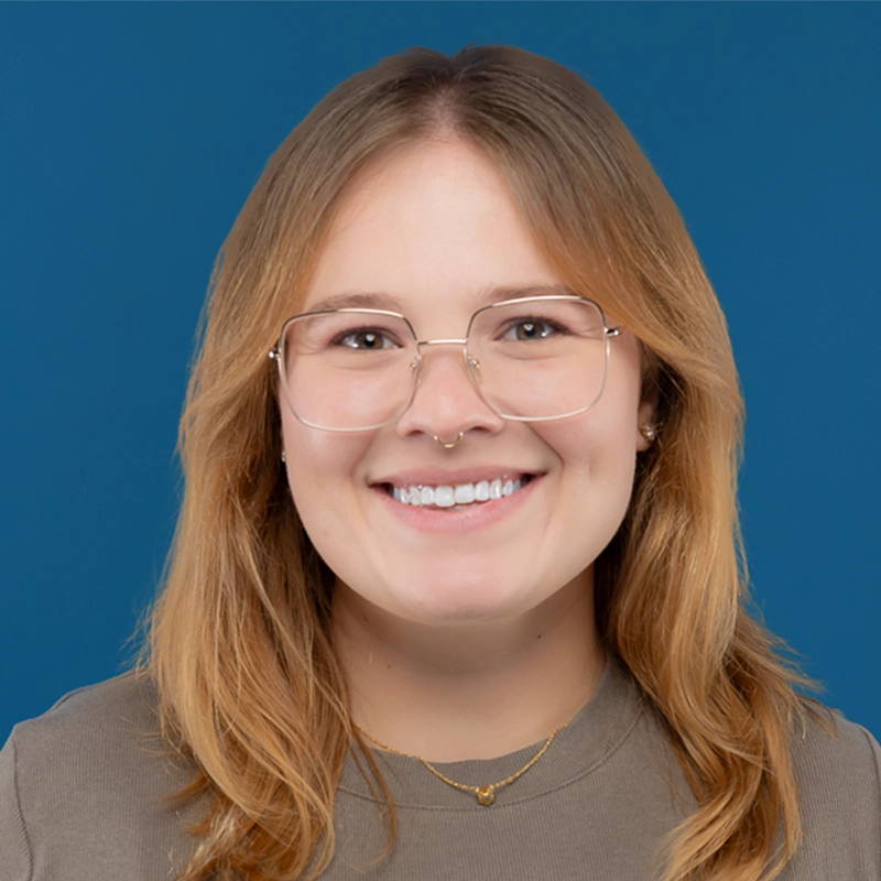 Chelsea Waterman smiles into the camera against a blue background.
