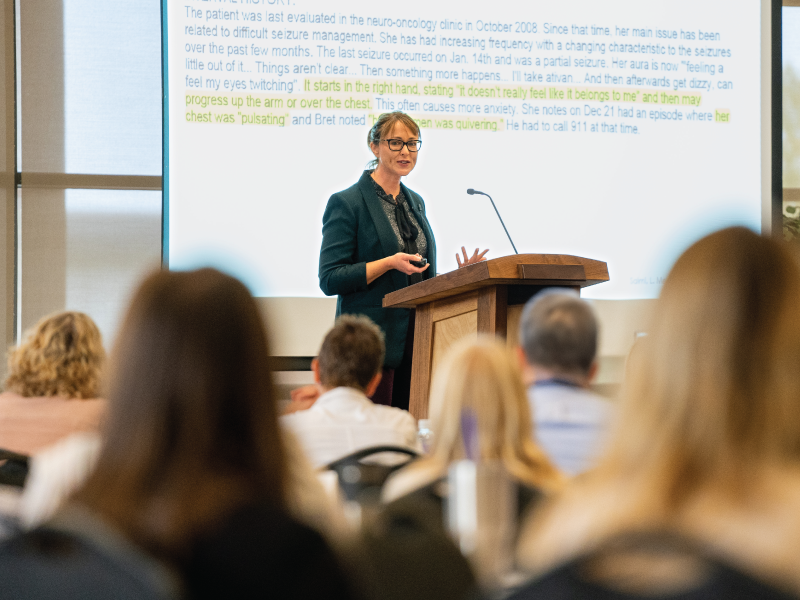 Person presenting at conference in front of crowd.